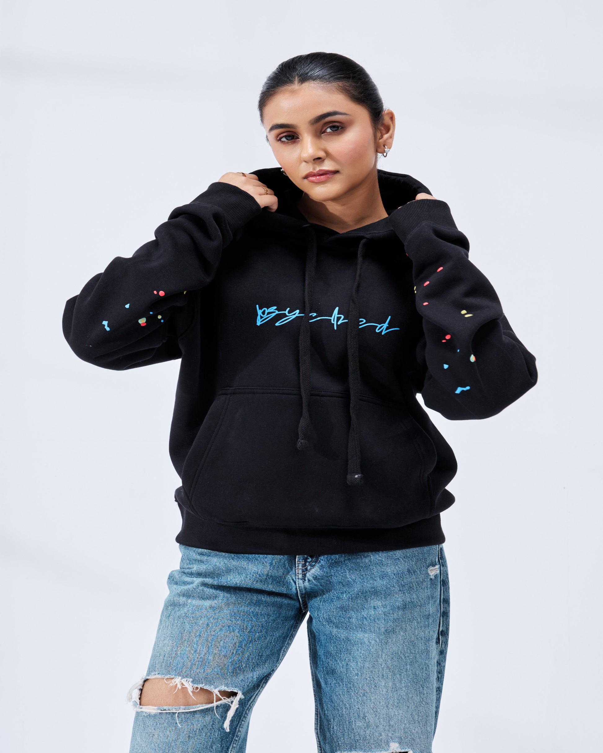 Person wearing a black hoodie with colorful designs on sleeves against a light gray background